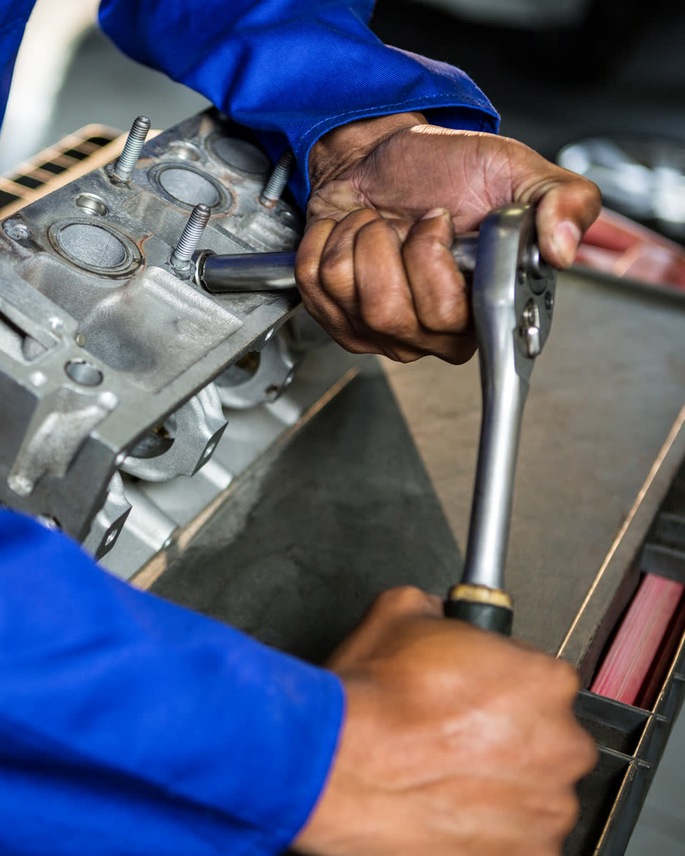 A technician using a ratchet on an engine part in a workshop